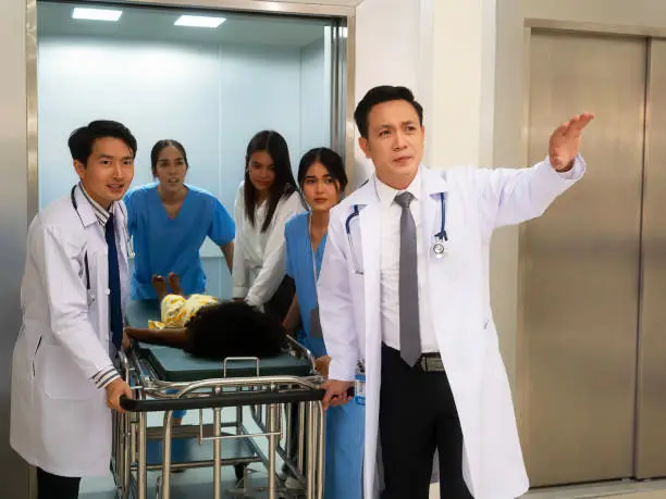doctors and nurse are coming out from a hospital bed lift with patient lying down on a stretcher